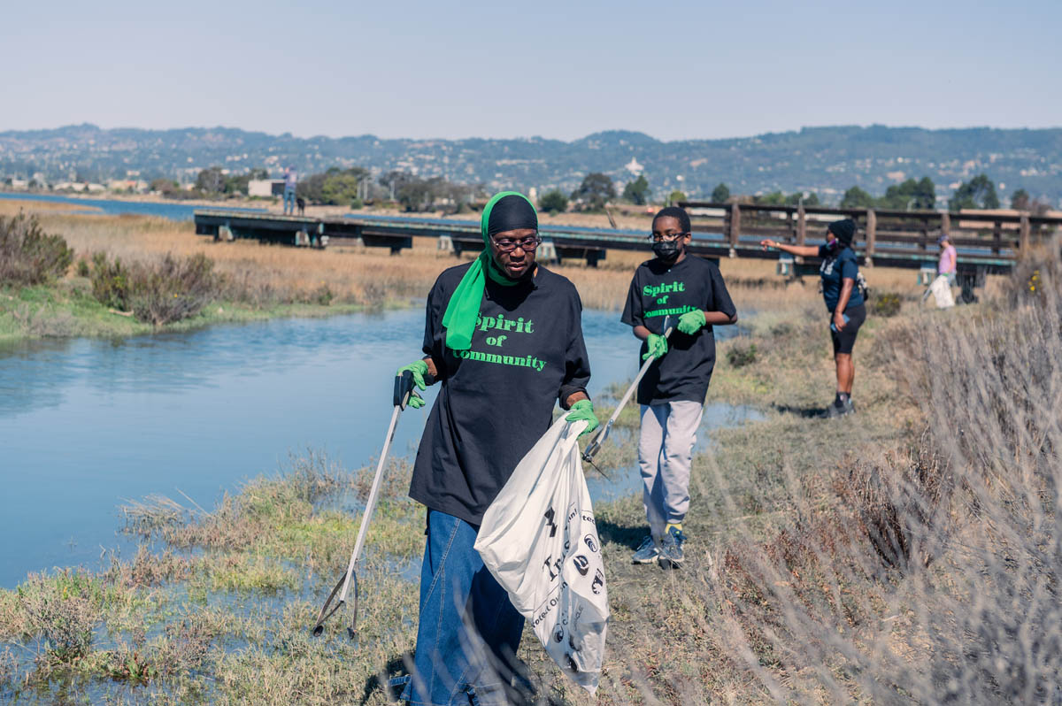 two people with Spirt of the community t-shorts work on cleaning the shore