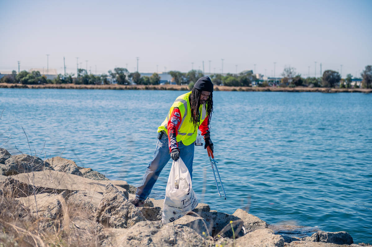 resident picks up waterfront trash and puts in bag