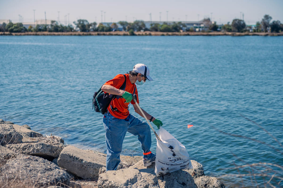 resident in orange shirt picks up beach litter