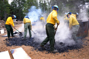 CCC workers rake out and extinguish the coals to save as much carbon as possible as biochar. Photo: David Morell.