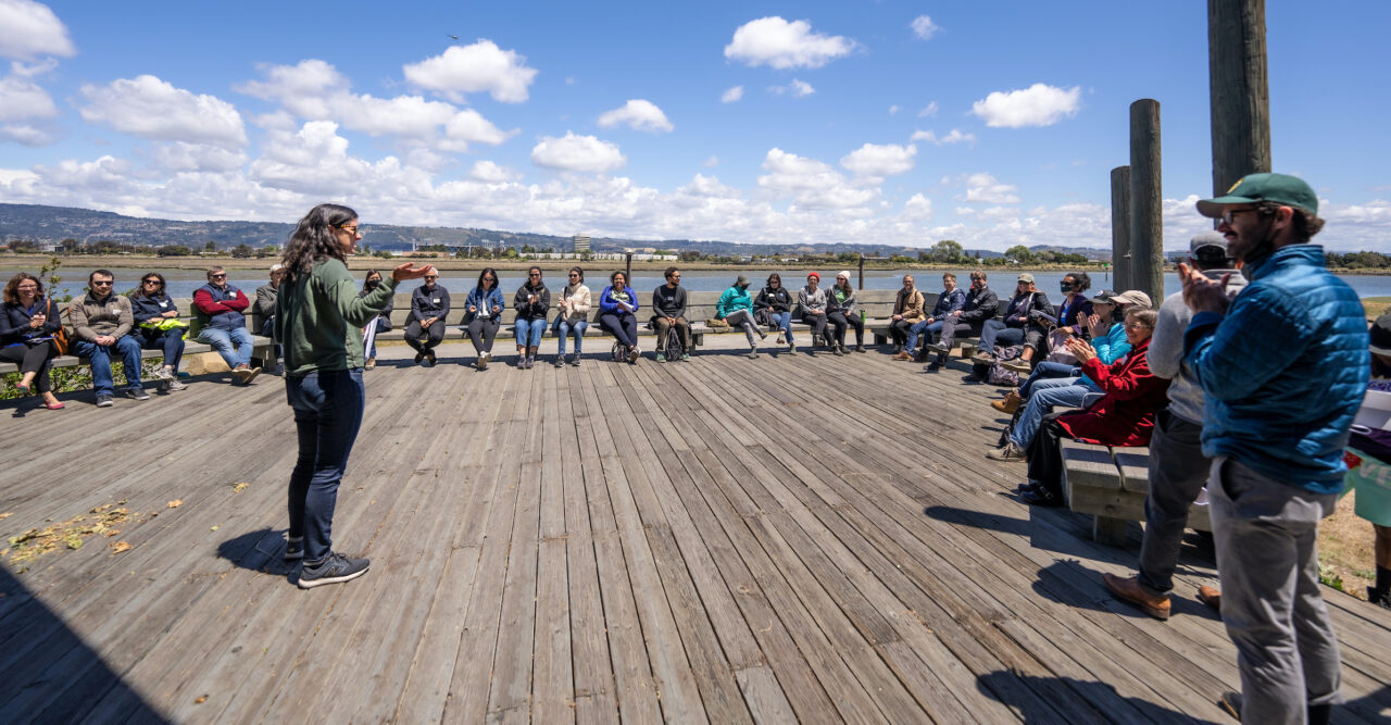 danielle mieler speaking to a crowd on alameda shore